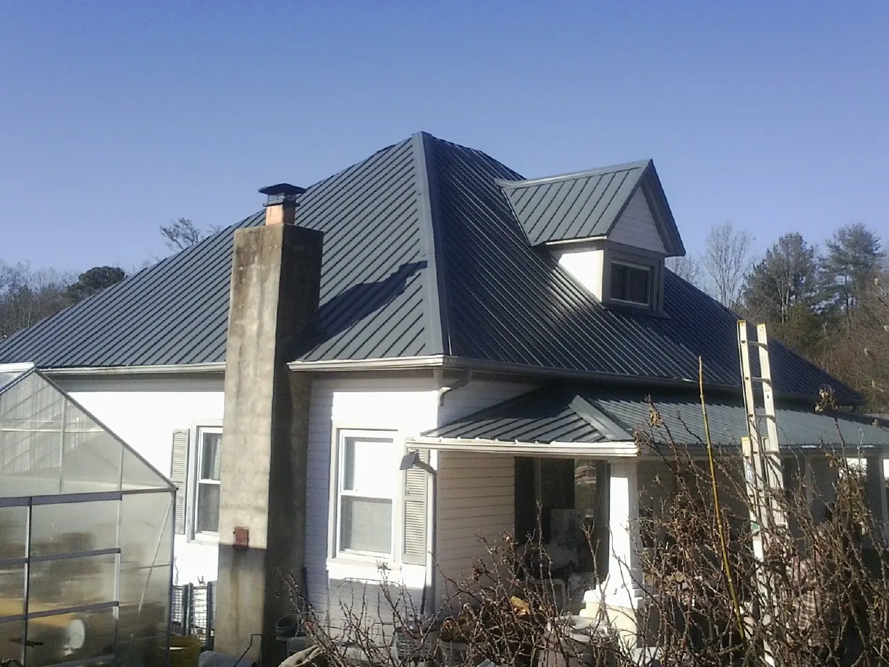 Dark blue standing seam metal roof on a white farmhouse with dormer — Slate & Tile Roof Repair by Roofing Brothers in Silverton