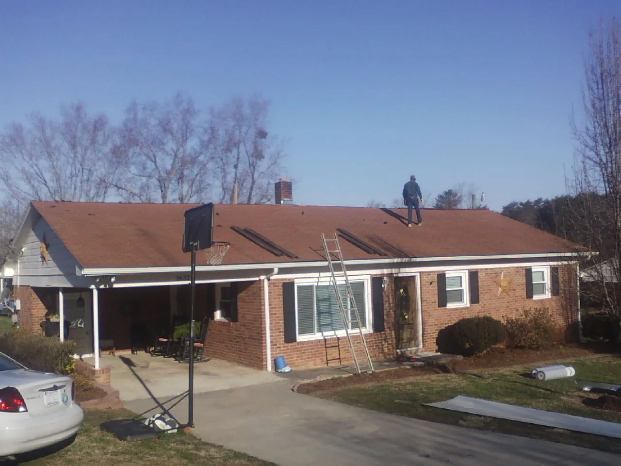 Roofer stripping a shingle roof on a brick ranch before metal panels in Silverton