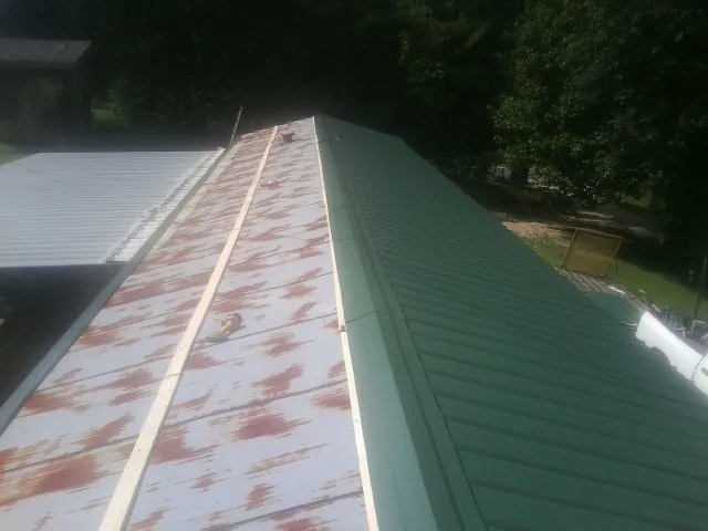 Old rusted panels beside newly installed green metal roofing — Wind Damage Roof Repair by Roofing Brothers in Silverton