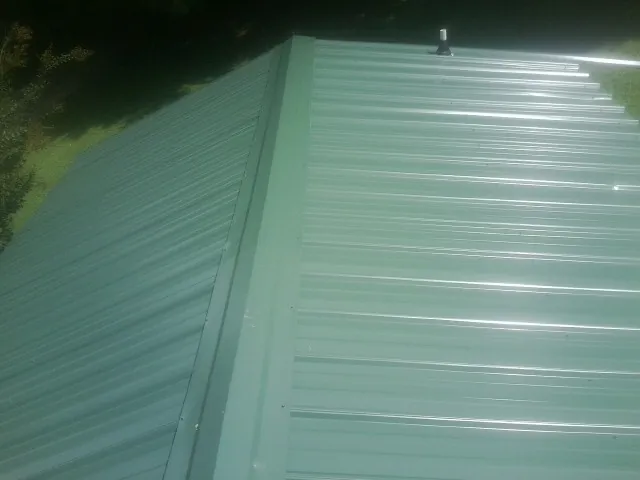 New green metal panels meeting at the ridge of a roof — Flat Roof Repair work by our crew in Silverton